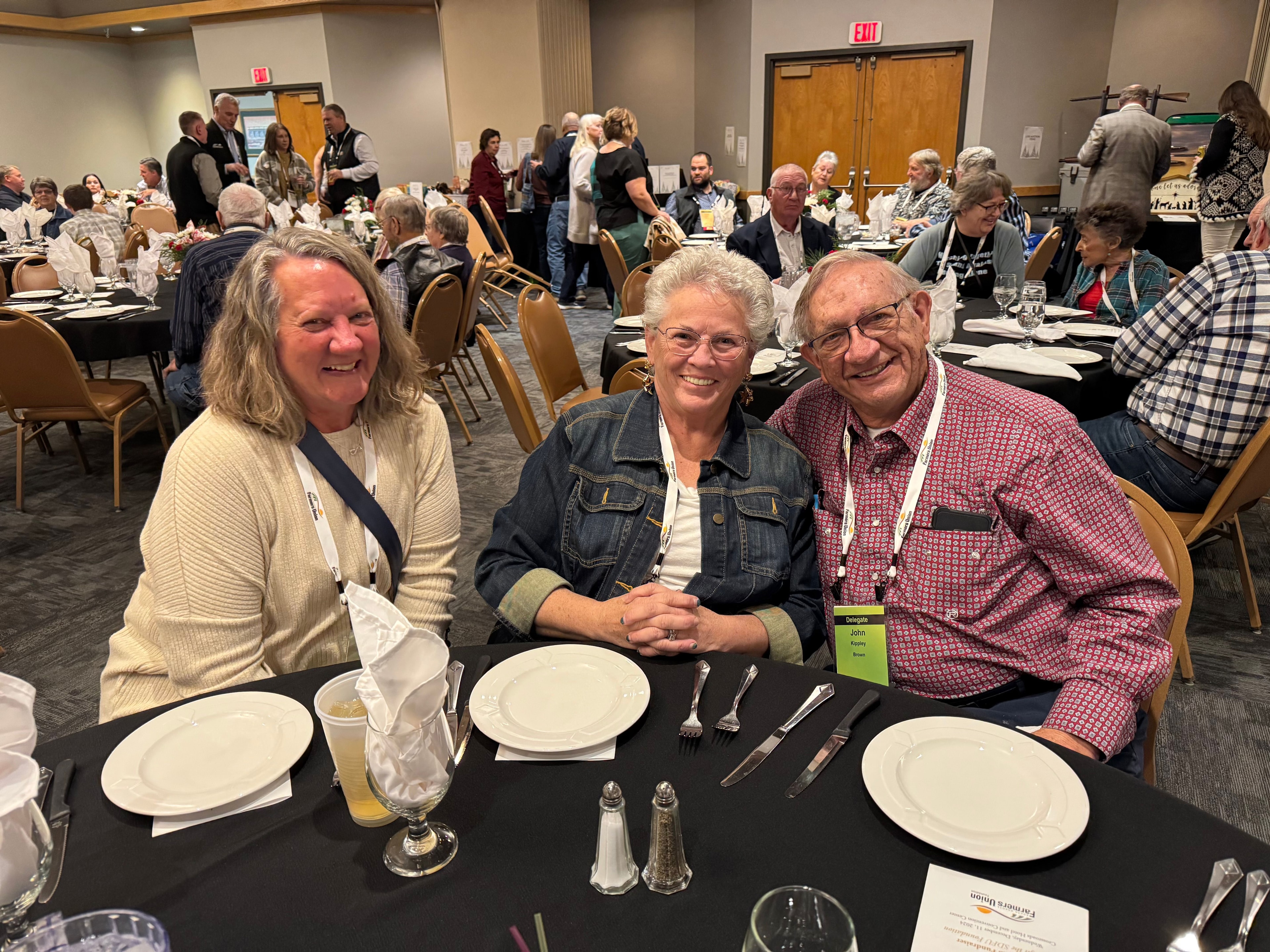 Three attendees smiling at the dinner table